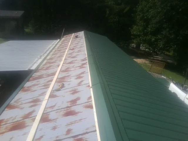 Old rusted panels beside newly installed green metal roofing — Wind Damage Roof Repair by Roofing Brothers in Cliffwood