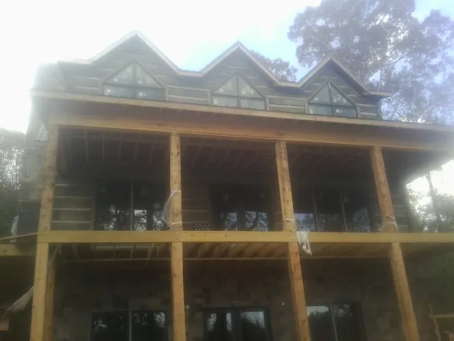 Dormers and porch framing on a large log home under construction — Roof Coating work by our crew in Cliffwood