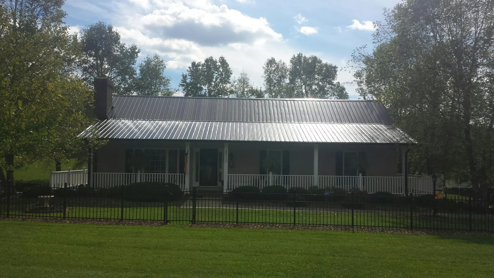 Gray metal roof on a brick ranch with a full width front porch — Gutter Guard Installation work by our crew in Cliffwood