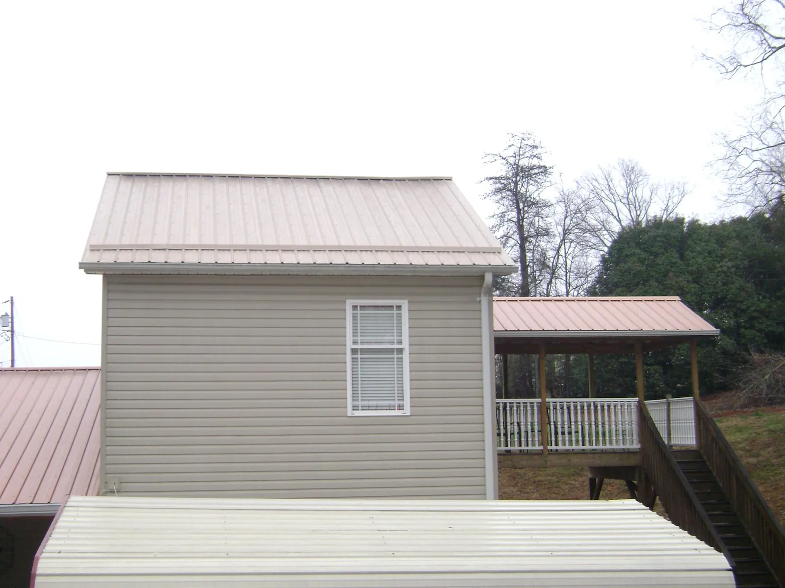 Tan metal roofs on a two story addition and attached porch, from a Roof Replacement job in Cliffwood
