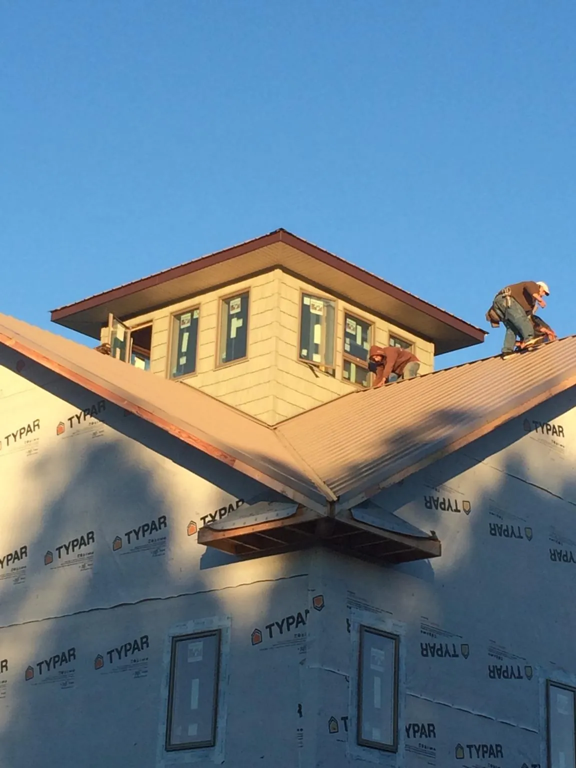 Roofers working around a rooftop cupola on a new metal roof at sunset — Roof Waterproofing in Cliffwood by Roofing Brothers